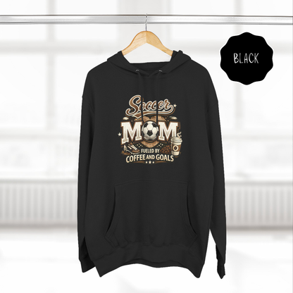 Black soccer mom hoodie hanging on a wooden hanger with fueled by coffee and goals graphic