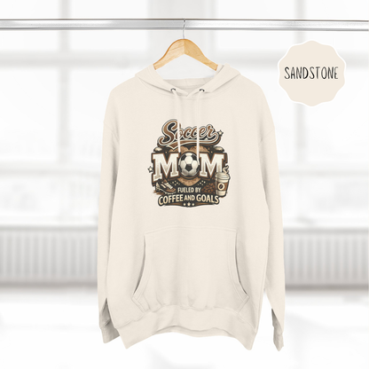 Neutral color soccer mom hoodie hanging on hanger with coffee and goals design