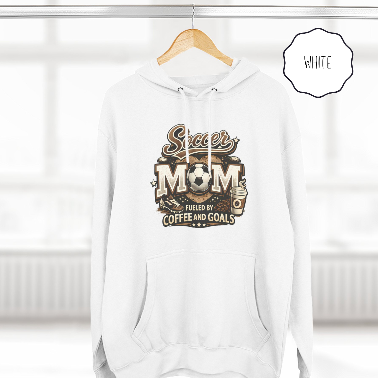 White soccer mom pullover hoodie hanging on hanger with fueled by coffee and goals print